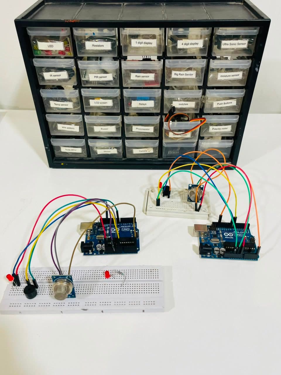 The studio's labelled parts drawers, with two Arduino boards wired to a gas sensor, an LED and a buzzer on breadboards