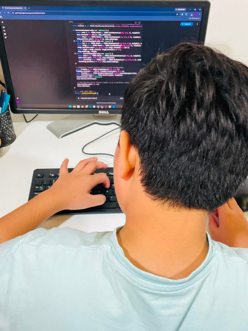 A student directing Google's Gemini AI to build a browser game, the code on screen